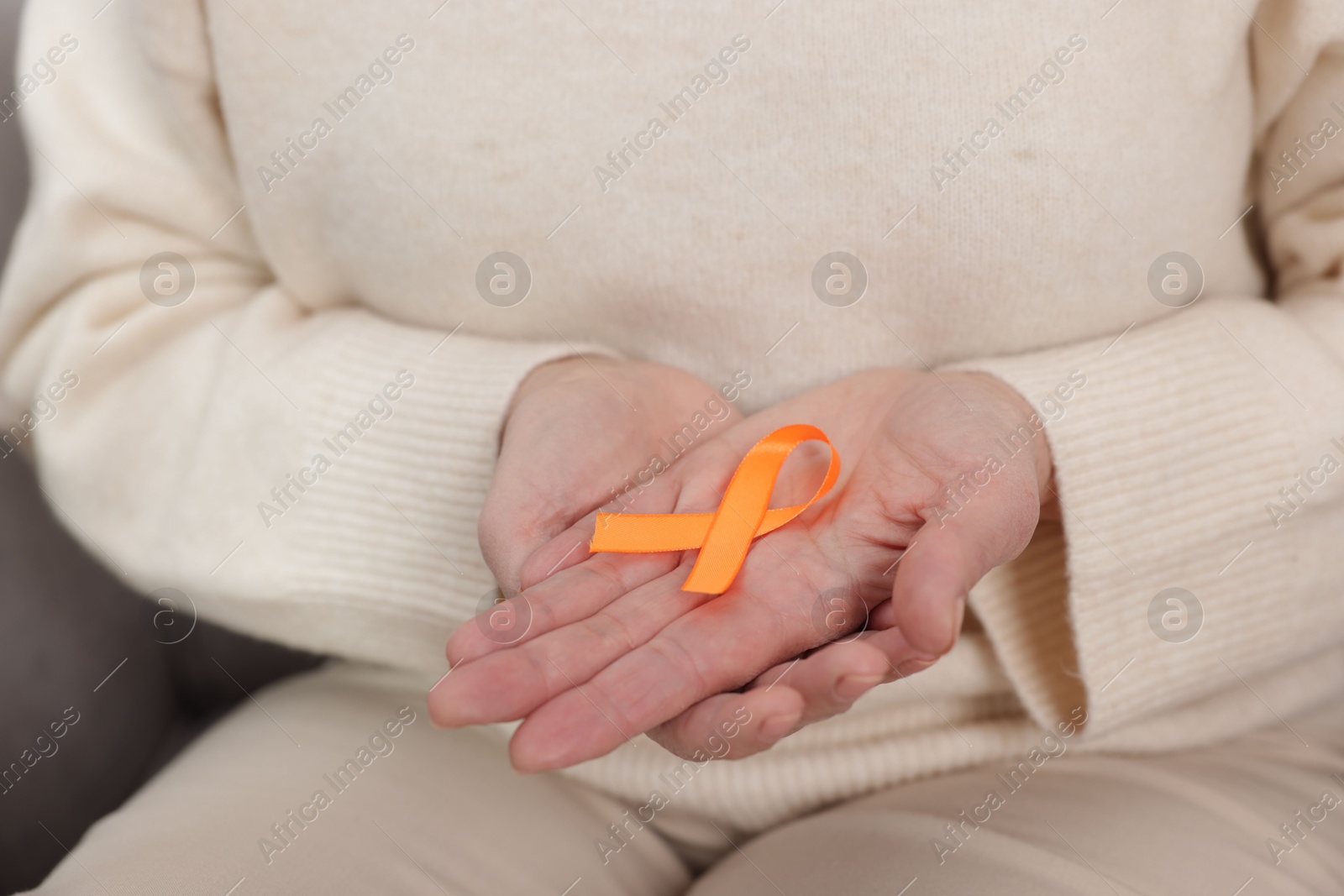 Photo of Multiple Sclerosis awareness. Woman with orange ribbon at home, closeup