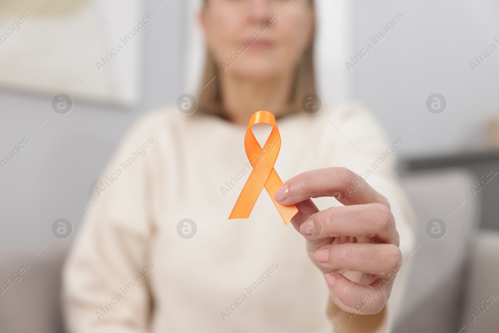 Photo of Multiple Sclerosis awareness. Woman with orange ribbon at home, closeup