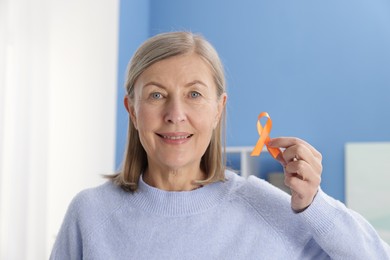 Photo of Multiple Sclerosis awareness. Woman with orange ribbon at home