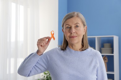 Photo of Multiple Sclerosis awareness. Woman with orange ribbon at home