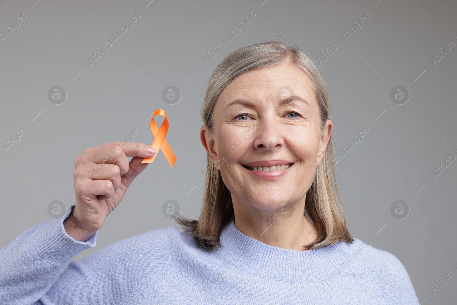 Photo of Multiple Sclerosis awareness. Woman with orange ribbon on light grey background