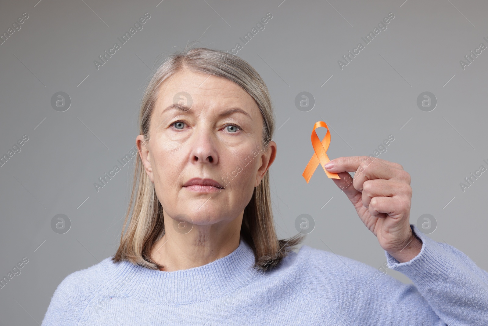 Photo of Multiple Sclerosis awareness. Woman with orange ribbon on light grey background