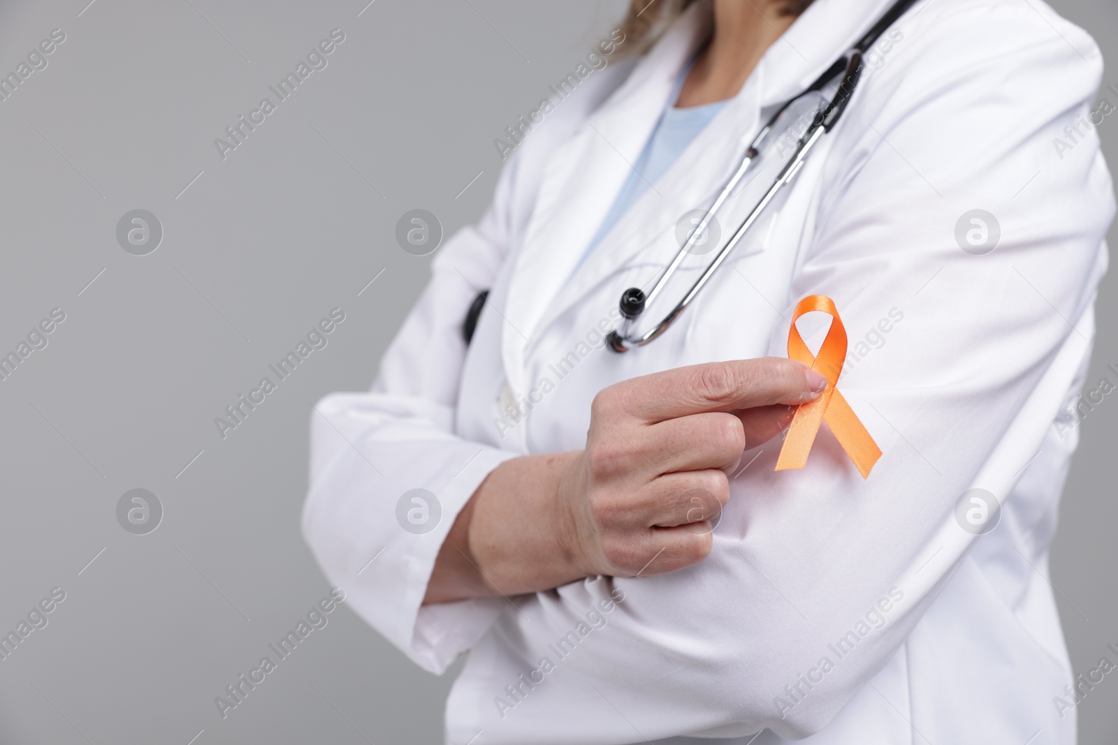 Photo of Multiple Sclerosis awareness. Doctor with orange ribbon on light grey background, closeup