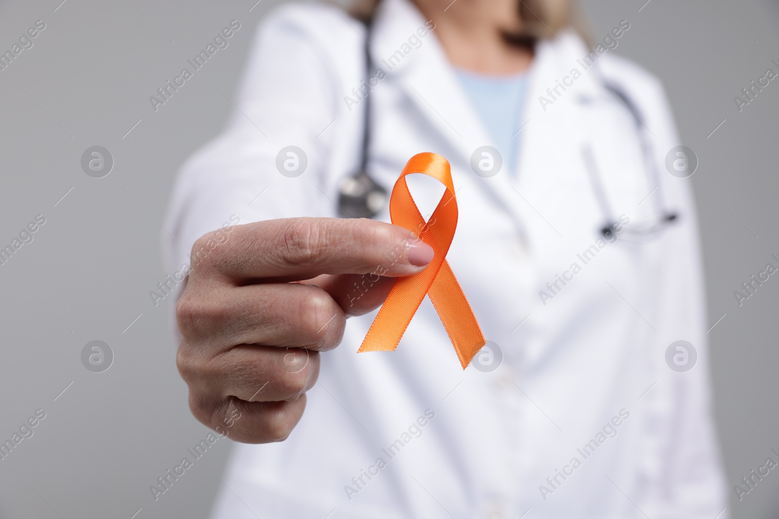 Photo of Multiple Sclerosis awareness. Doctor with orange ribbon on light grey background, closeup