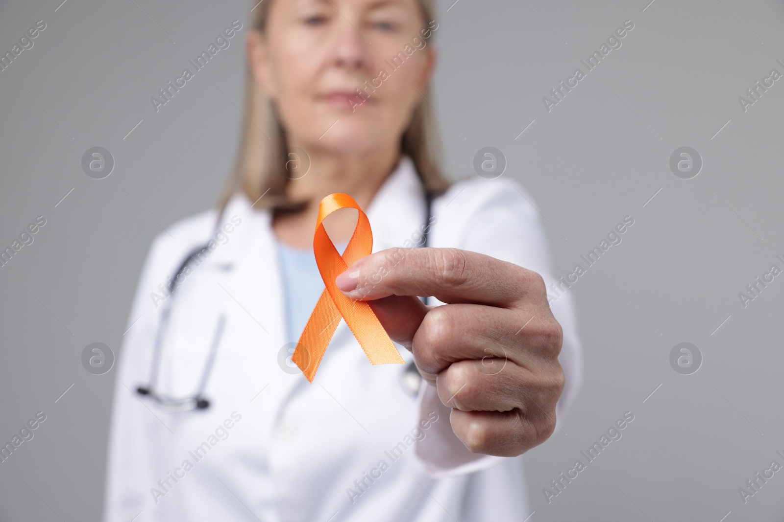 Photo of Multiple Sclerosis awareness. Doctor with orange ribbon on light grey background, selective focus