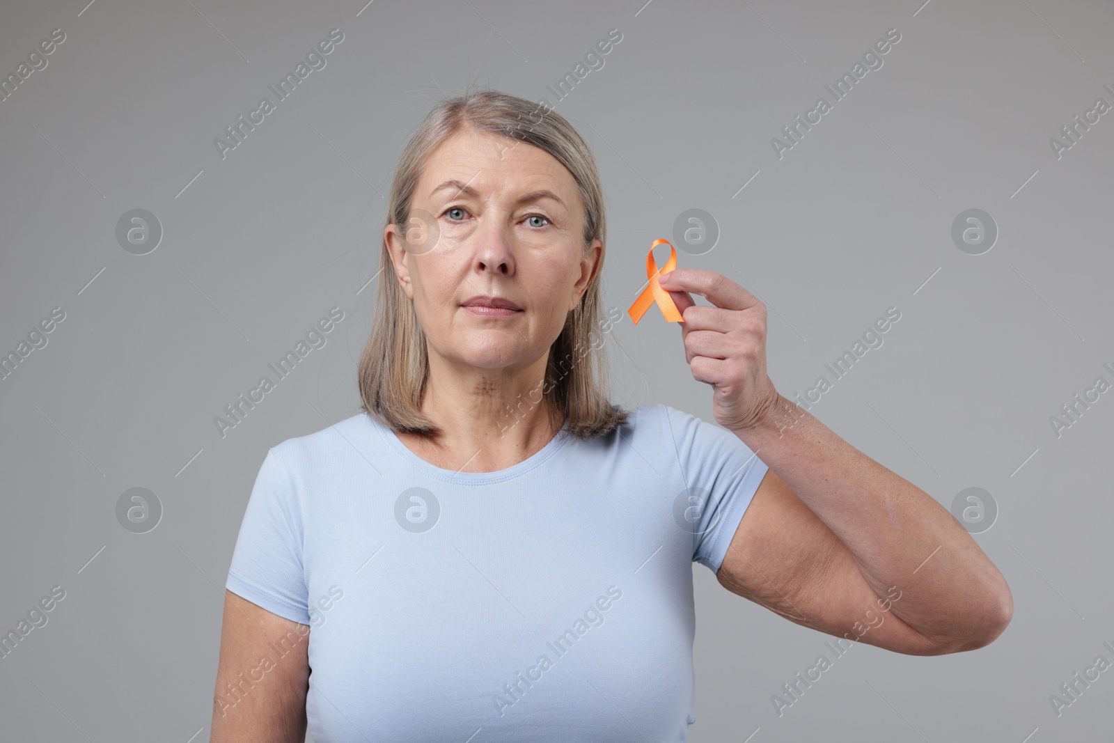 Photo of Multiple Sclerosis awareness. Woman with orange ribbon on light grey background