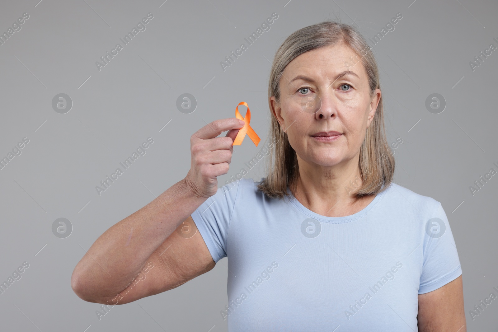 Photo of Multiple Sclerosis awareness. Woman with orange ribbon on light grey background