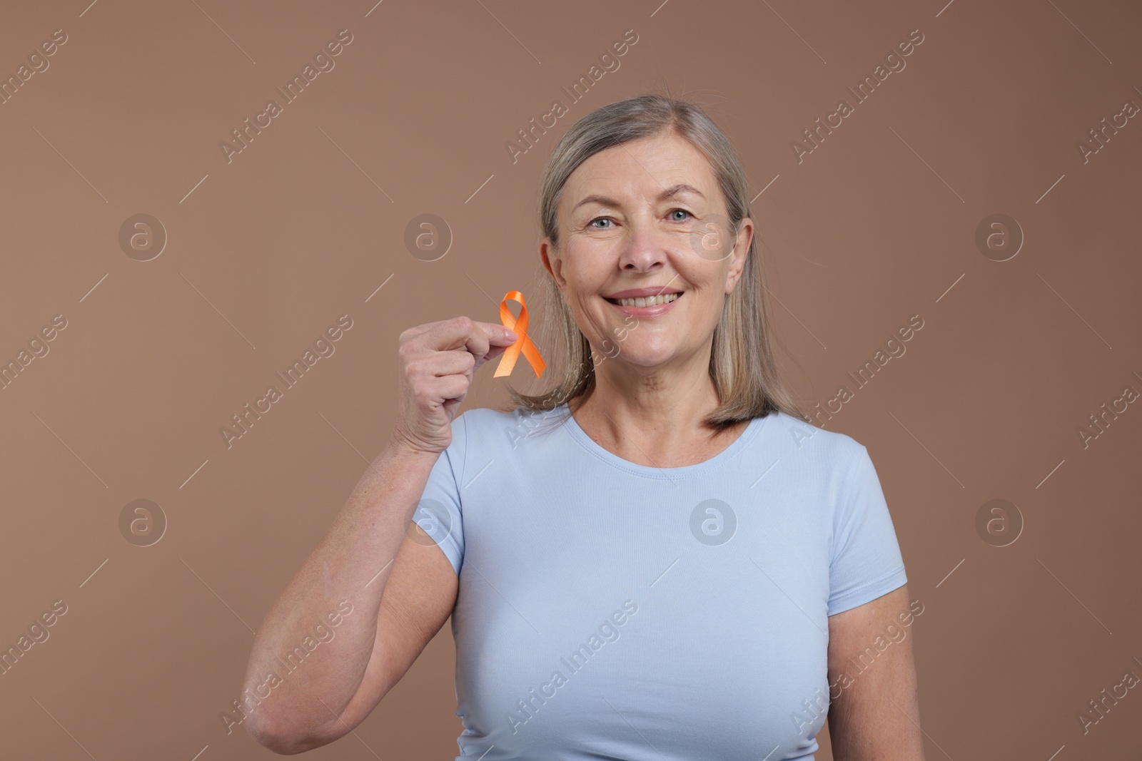 Photo of Multiple Sclerosis awareness. Woman with orange ribbon on brown background