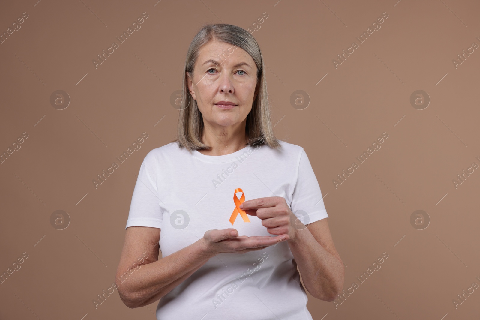 Photo of Multiple Sclerosis awareness. Woman with orange ribbon on brown background