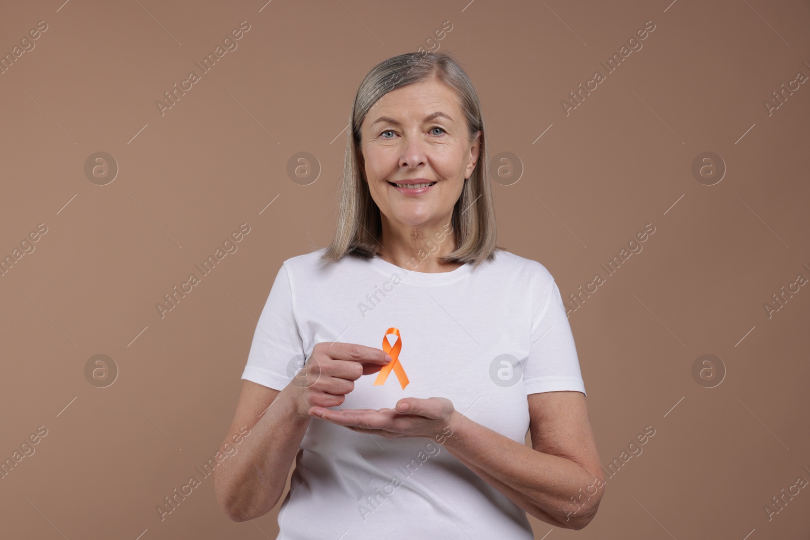 Photo of Multiple Sclerosis awareness. Woman with orange ribbon on brown background