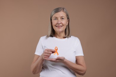 Photo of Multiple Sclerosis awareness. Woman with orange ribbon on brown background