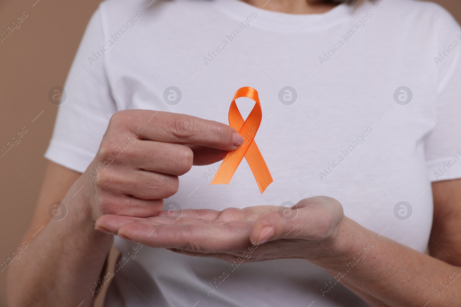 Photo of Multiple Sclerosis awareness. Woman with orange ribbon on brown background, closeup