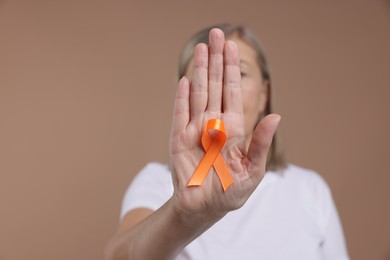 Photo of Multiple Sclerosis awareness. Woman with orange ribbon on brown background