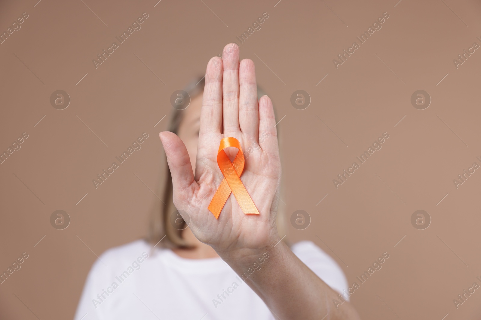 Photo of Multiple Sclerosis awareness. Woman with orange ribbon on brown background