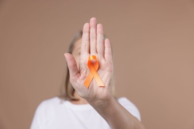 Photo of Multiple Sclerosis awareness. Woman with orange ribbon on brown background