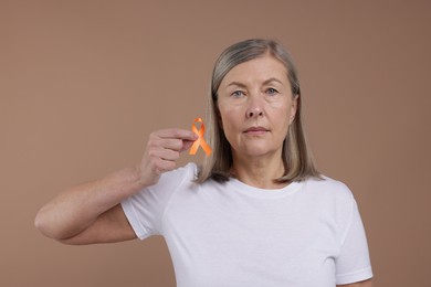 Multiple Sclerosis awareness. Woman with orange ribbon on brown background