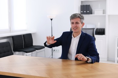 Photo of Man showing something at desk in office. Space for text