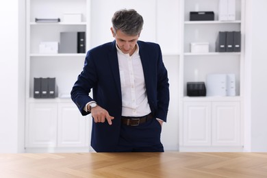 Photo of Man pointing at something on desk in office