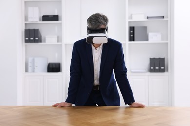 Photo of Man using virtual reality headset at desk in office