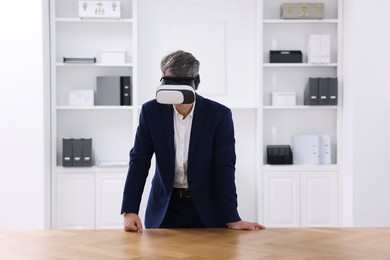 Photo of Man using virtual reality headset at desk in office