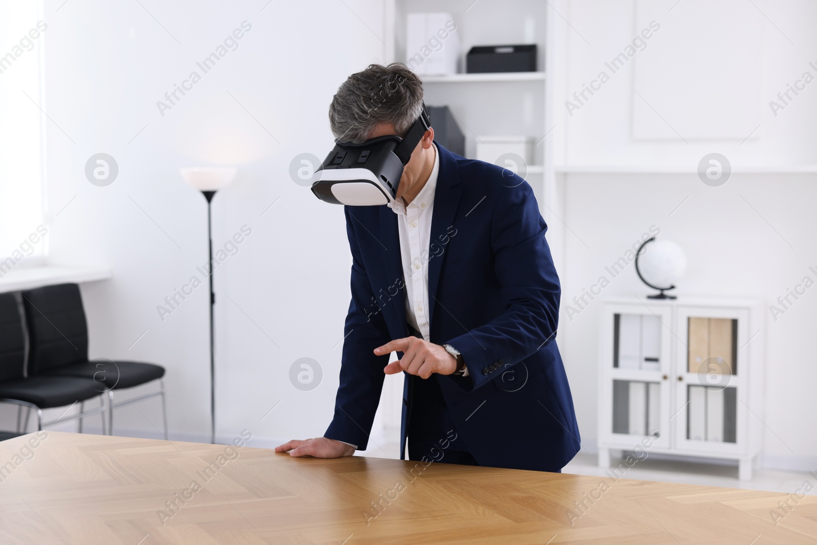 Photo of Man using virtual reality headset at desk in office