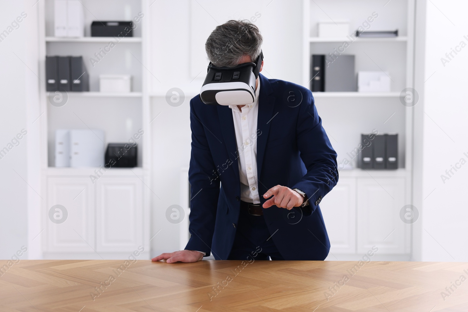 Photo of Man using virtual reality headset at desk in office