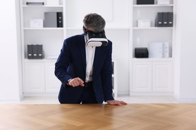 Photo of Man using virtual reality headset at desk in office