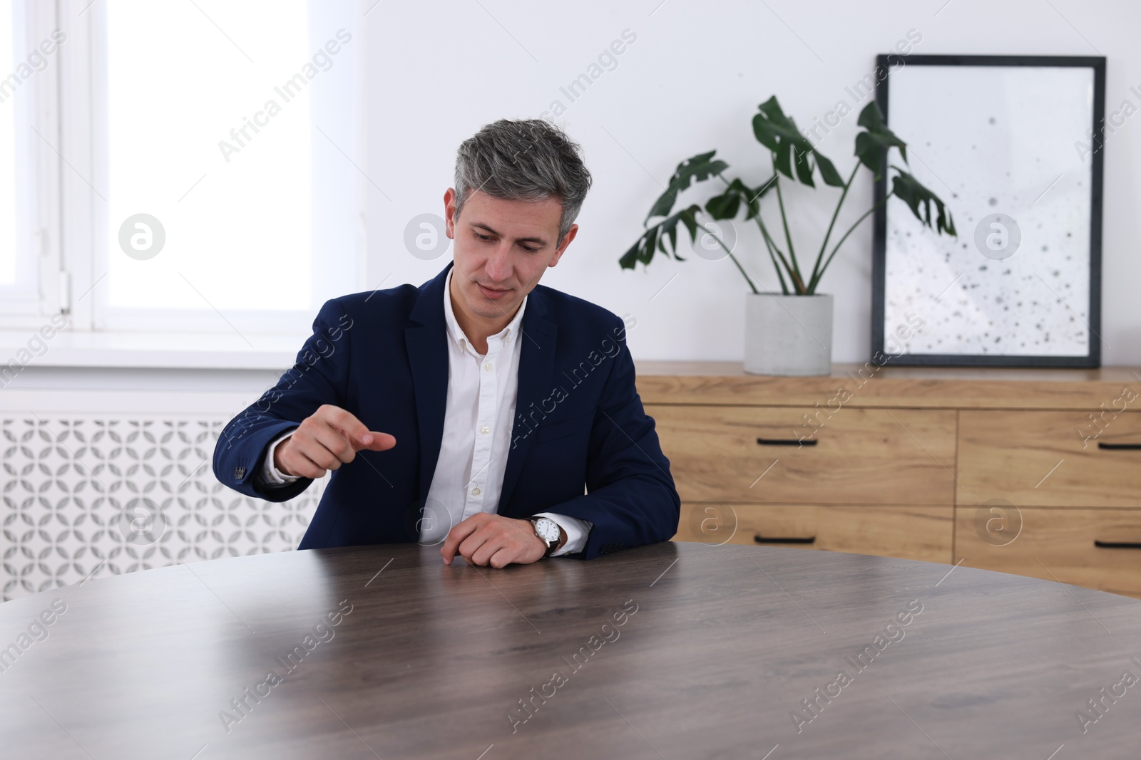 Photo of Man pointing at something on desk in office