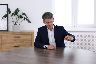 Photo of Man pointing at something on desk in office