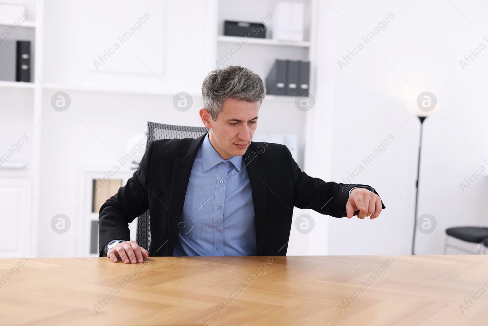 Photo of Man pointing at something on desk in office