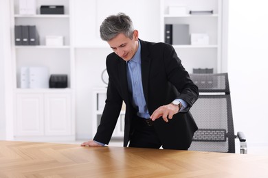 Photo of Man pointing at something on desk in office