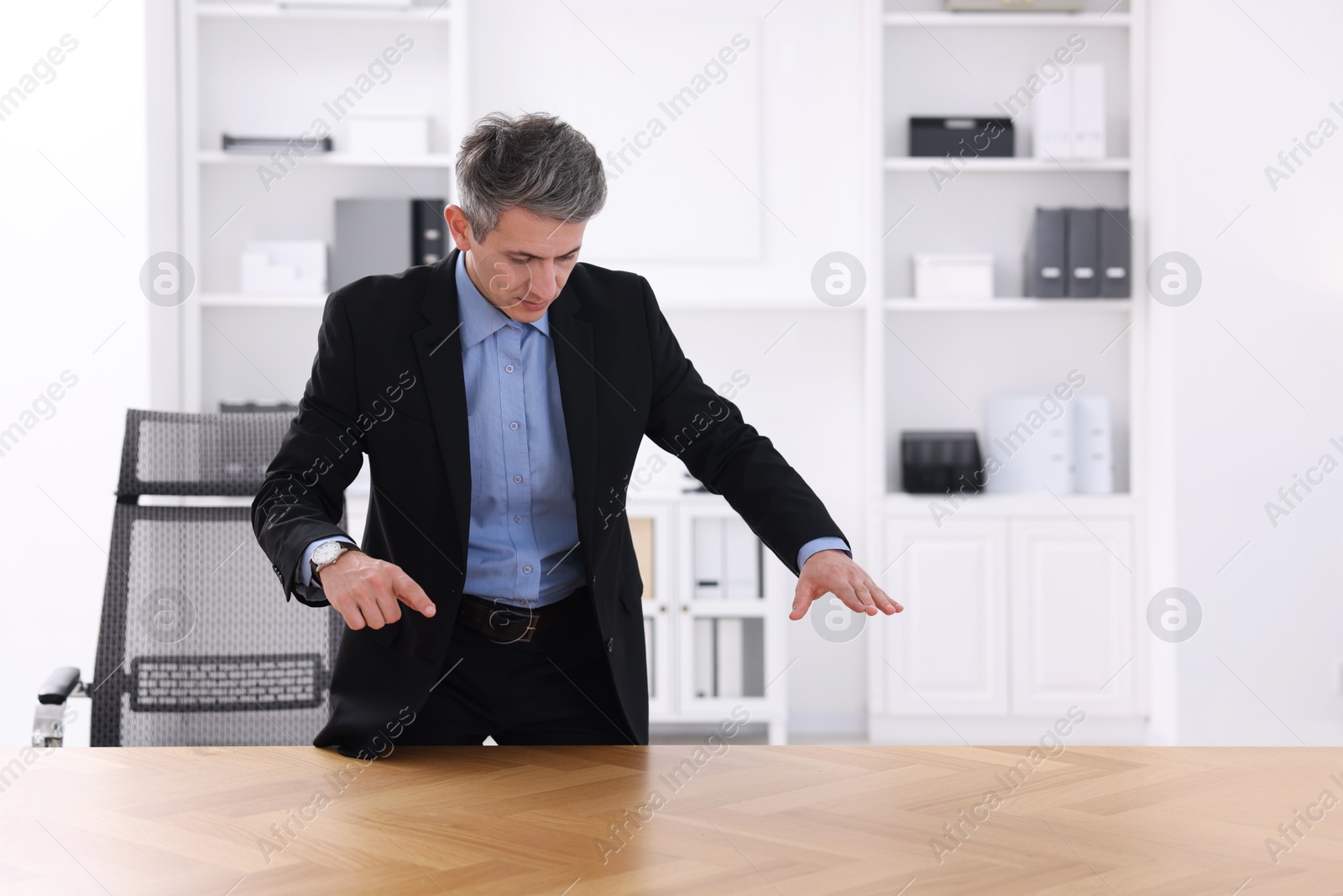 Photo of Man showing something at desk in office