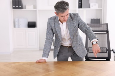 Photo of Man pointing at something on desk in office