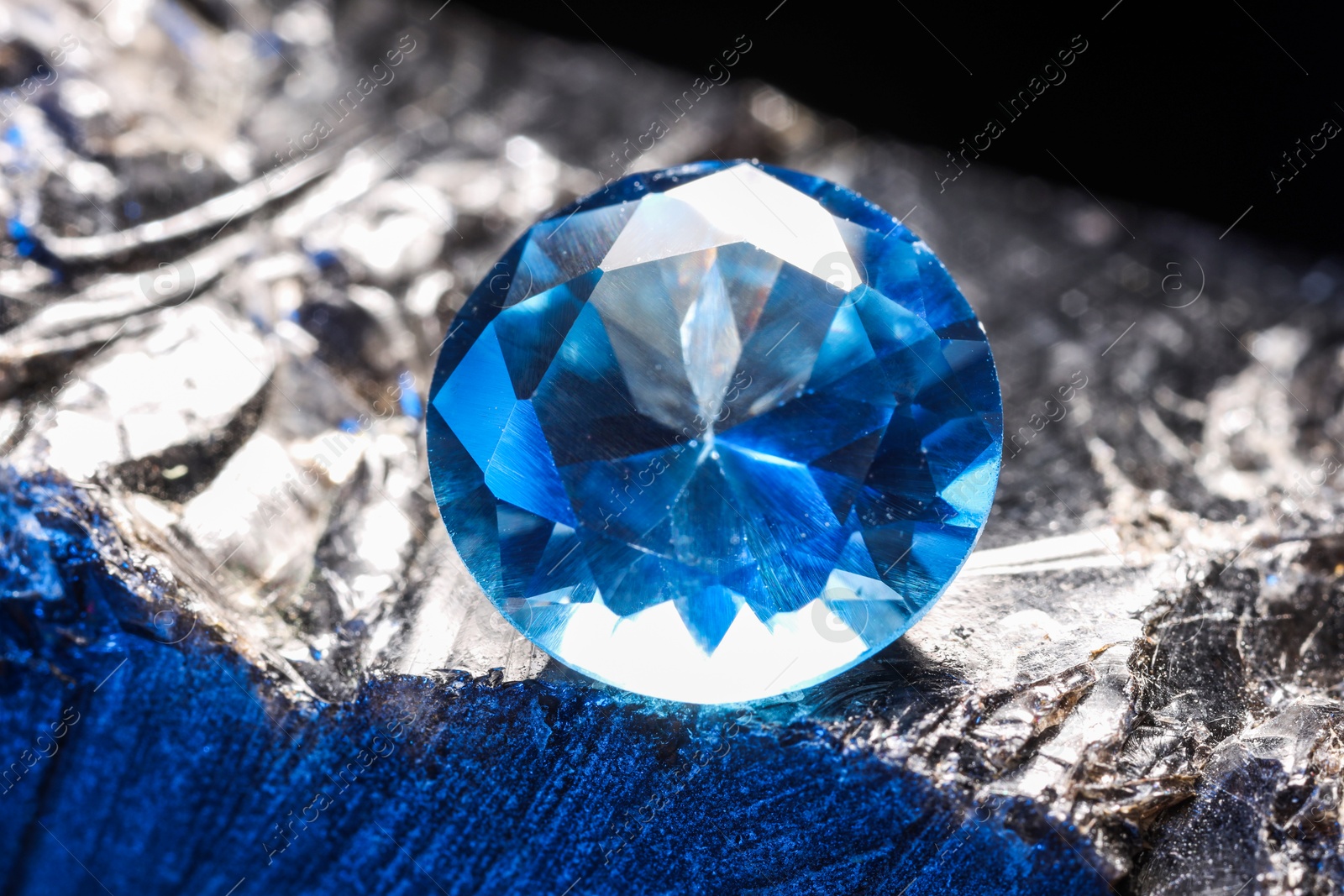 Photo of Beautiful shiny light blue gemstone on stone, closeup