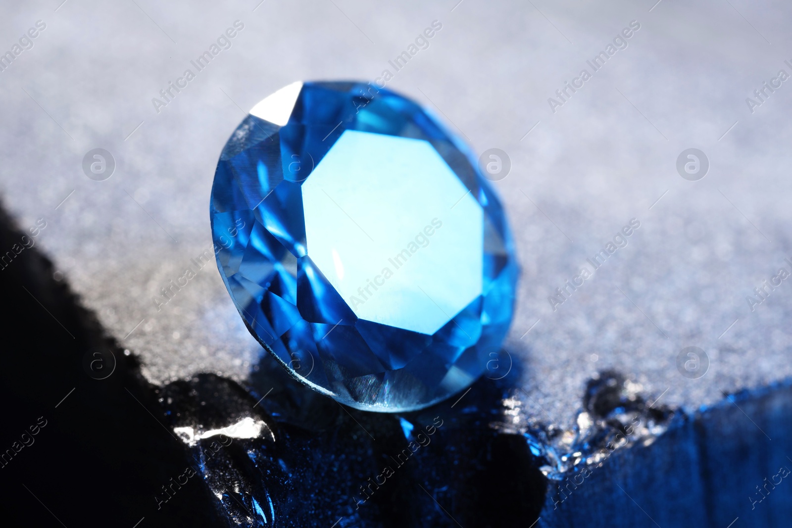 Photo of Beautiful shiny light blue gemstone on stone, closeup