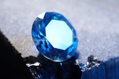 Photo of Beautiful shiny light blue gemstone on stone, closeup