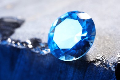 Photo of Beautiful shiny light blue gemstone on stone, closeup