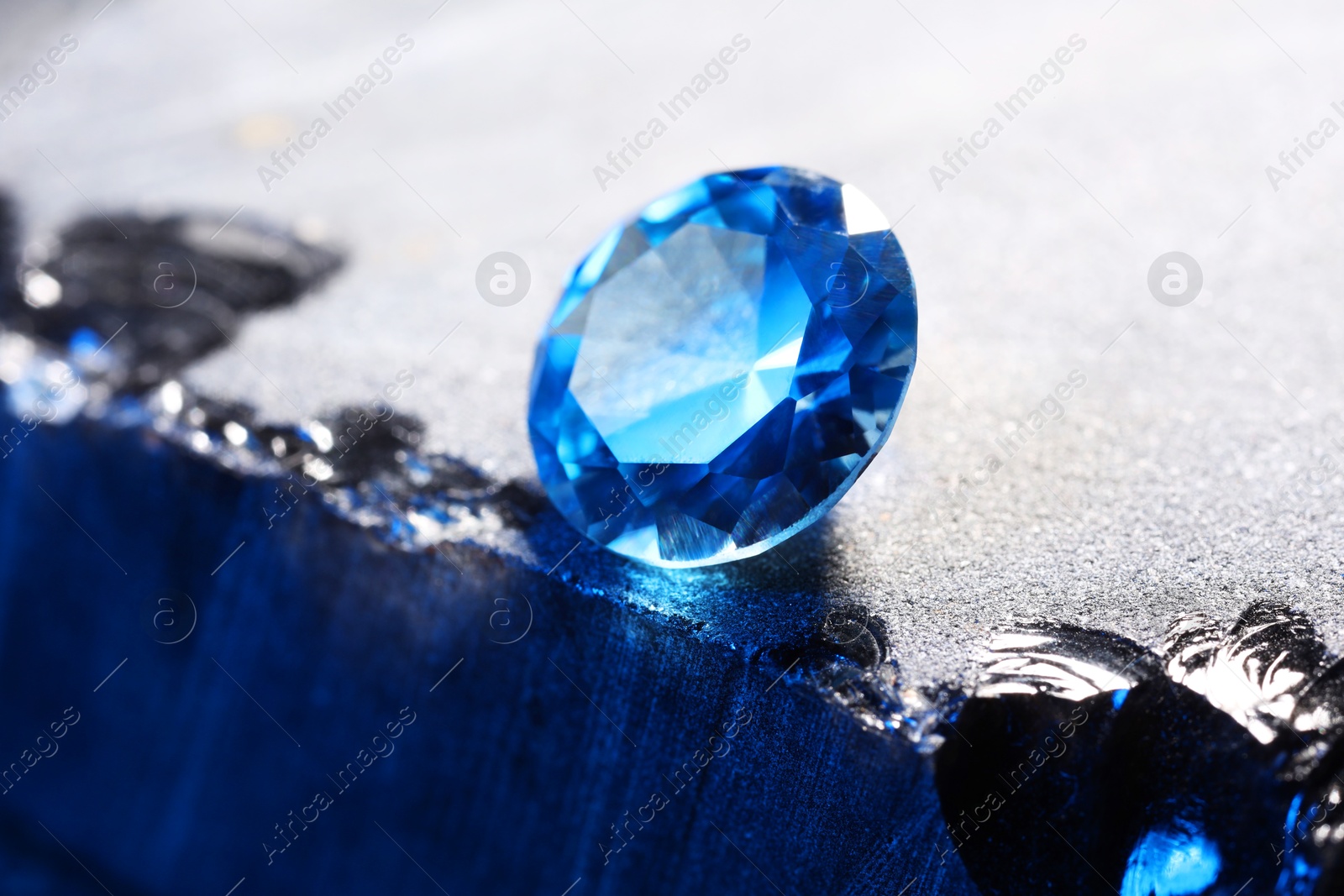 Photo of Beautiful shiny light blue gemstone on stone, closeup