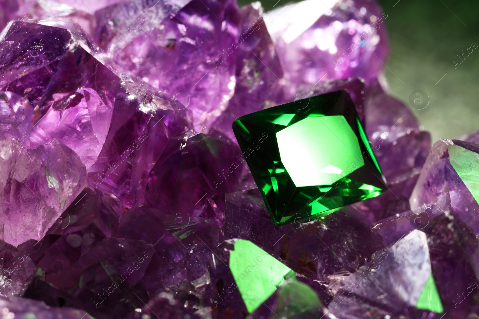 Photo of Beautiful shiny green gemstone on natural amethyst, closeup