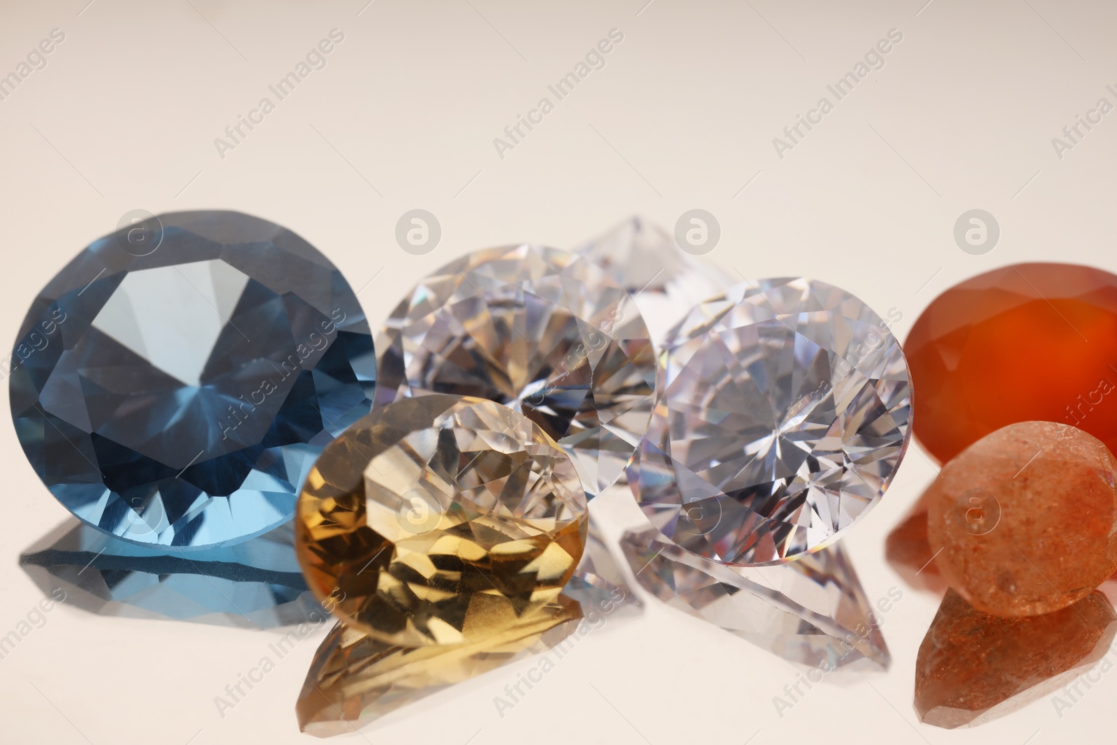 Photo of Beautiful shiny colorful gemstones on light background, closeup