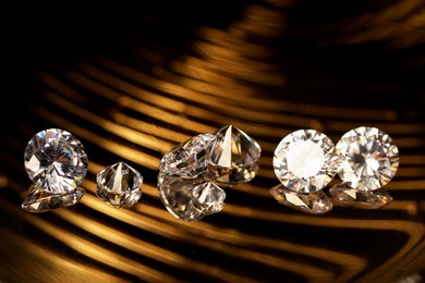 Photo of Beautiful shiny gemstones on golden tray in dark, closeup