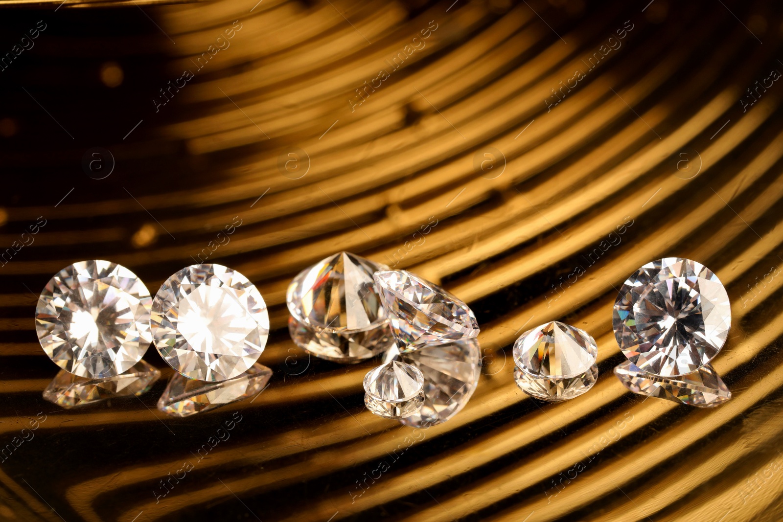 Photo of Beautiful shiny gemstones on golden tray, closeup