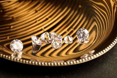 Photo of Beautiful shiny gemstones on golden tray, closeup