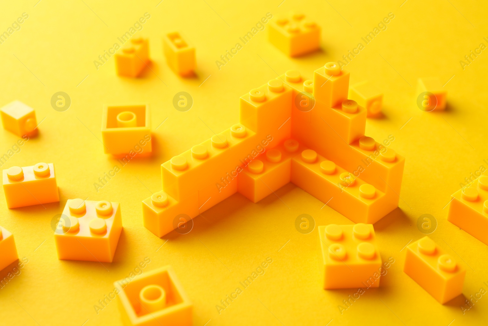 Photo of Constructor toy. Many building blocks on yellow background, closeup