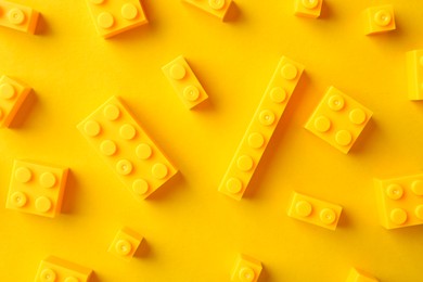 Photo of Constructor toy. Many building blocks on yellow background, flat lay