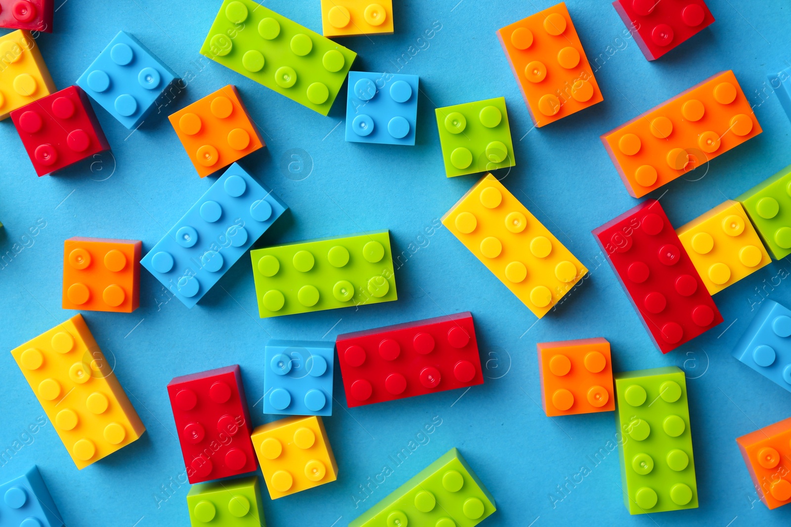 Photo of Constructor toy. Many colorful building blocks on light blue background, flat lay