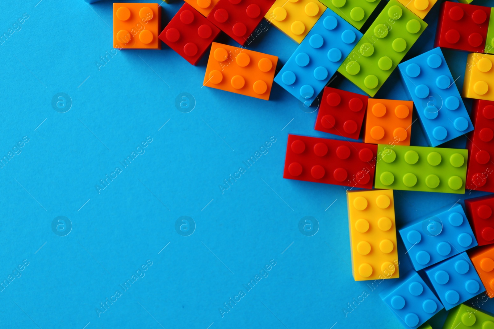 Photo of Constructor toy. Many colorful building blocks on light blue background, flat lay. Space for text