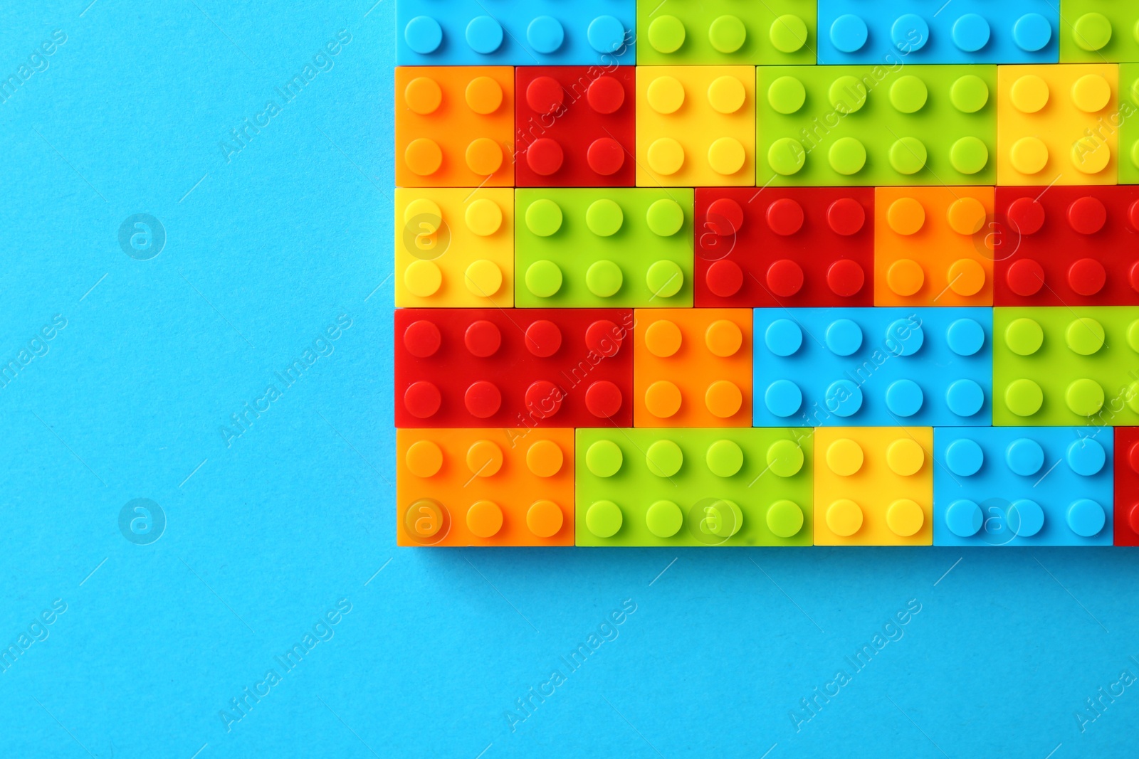 Photo of Constructor toy. Many colorful building blocks on light blue background, top view. Space for text