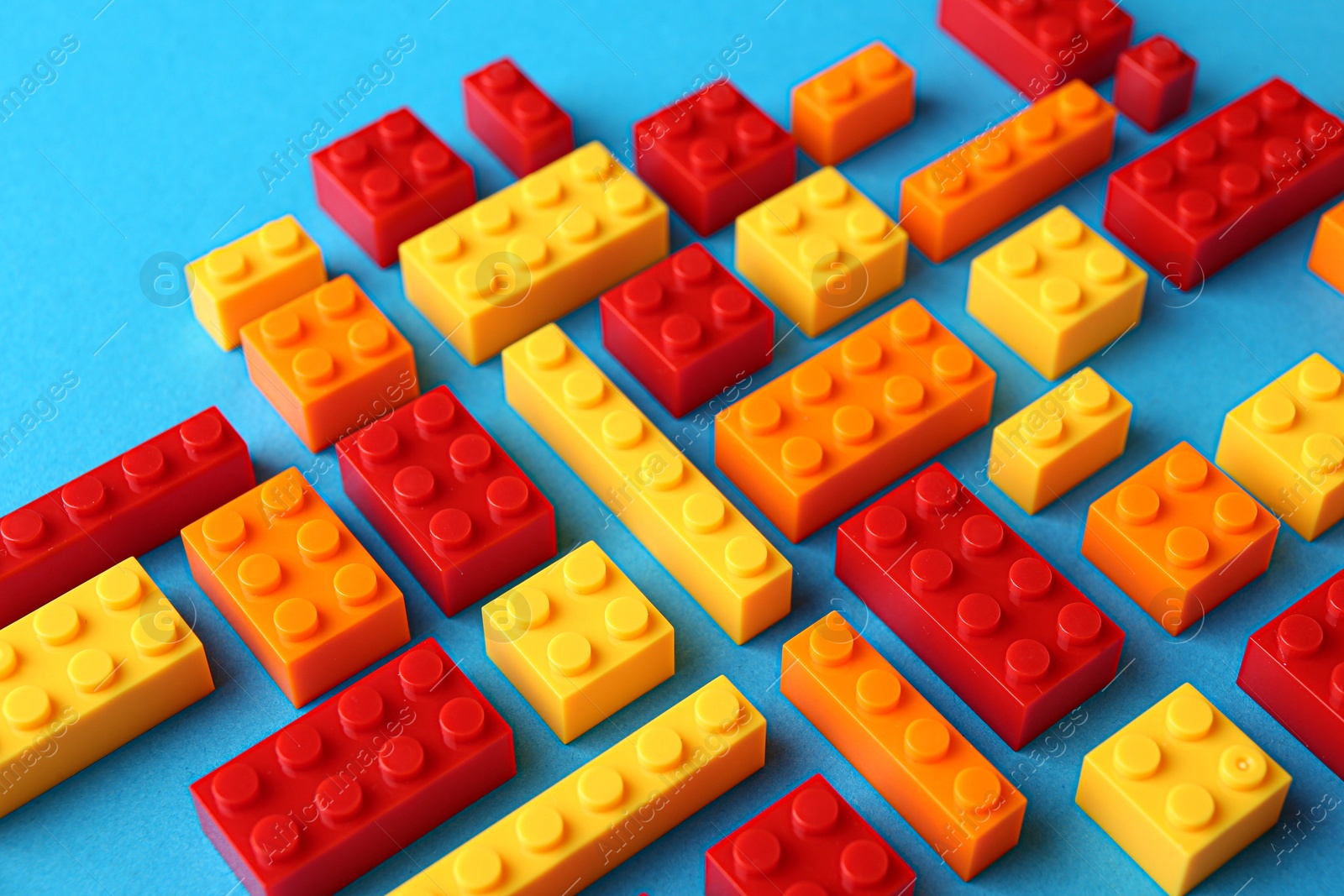 Photo of Constructor toy. Many colorful building blocks on light blue background, closeup