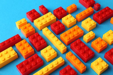 Photo of Constructor toy. Many colorful building blocks on light blue background, closeup